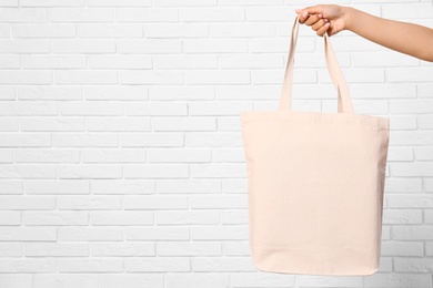 Photo of Woman with stylish blank eco bag near brick wall, closeup. Space for text