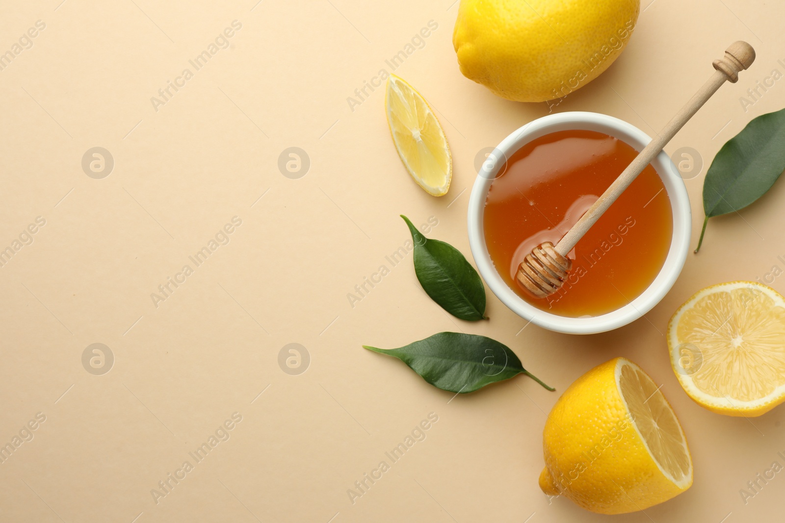 Photo of Ripe lemons, leaves, bowl of honey and dipper on beige background, flat lay. Space for text