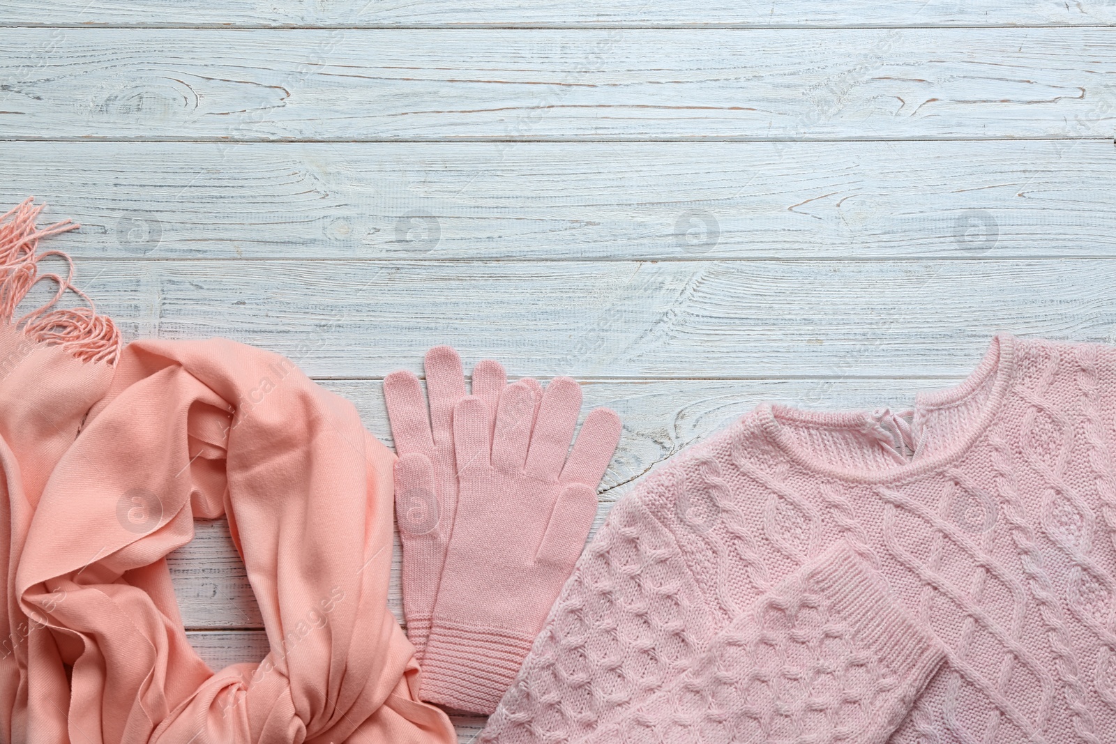 Photo of Flat lay composition with warm clothes on white wooden background. Space for text