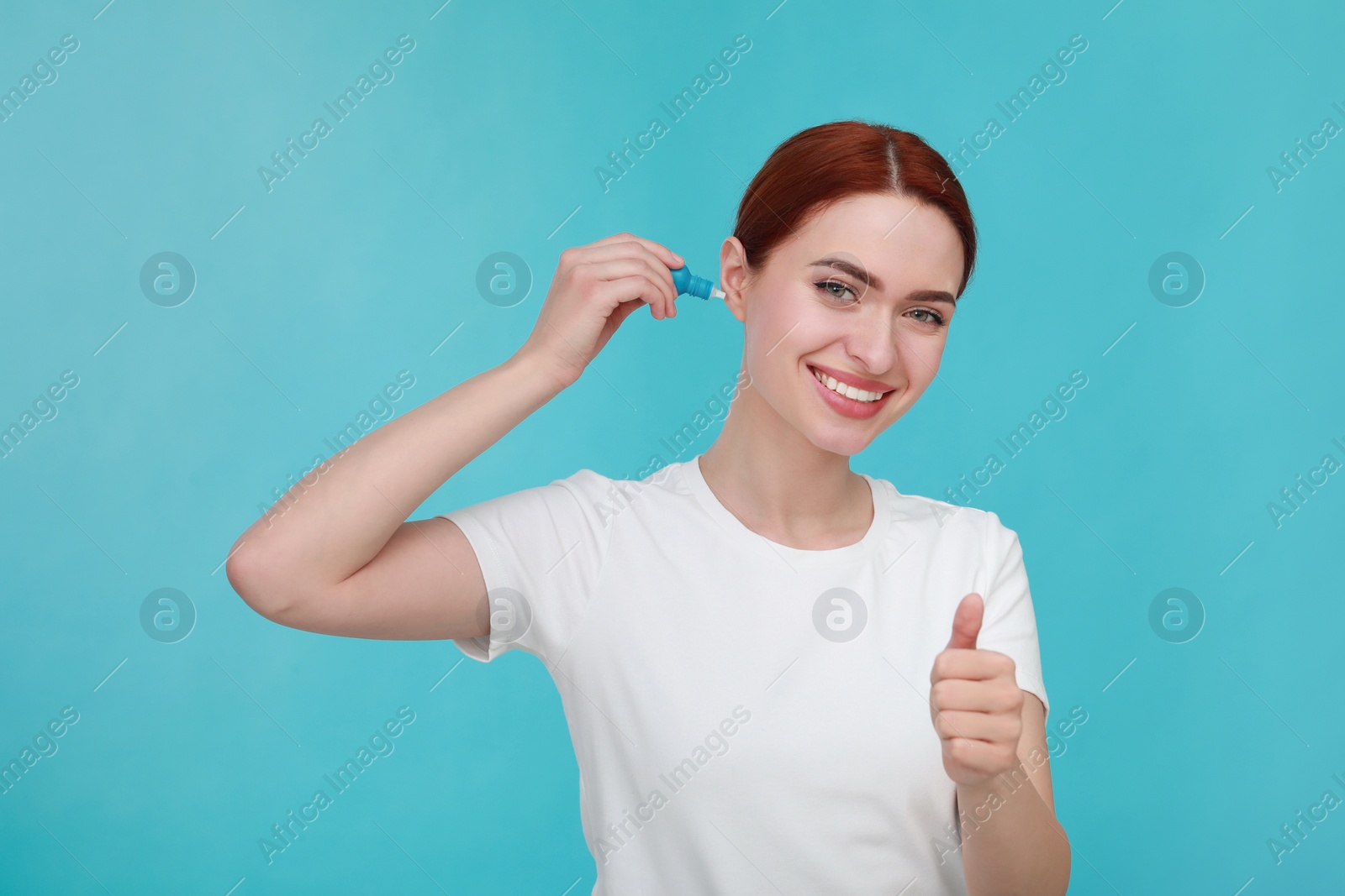 Photo of Woman using ear drops on light blue background