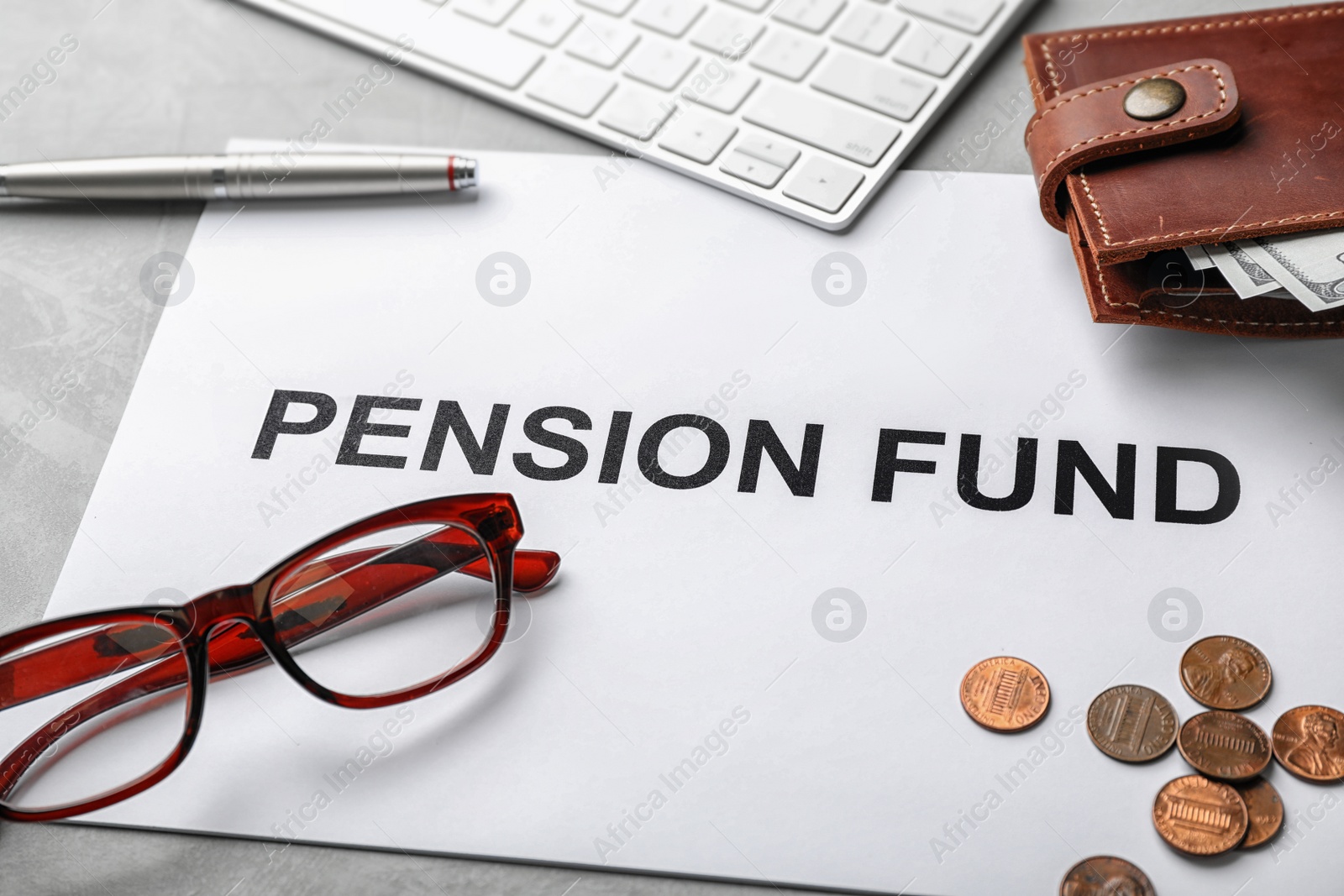 Photo of Composition of paper with words PENSION FUND, glasses and money on table