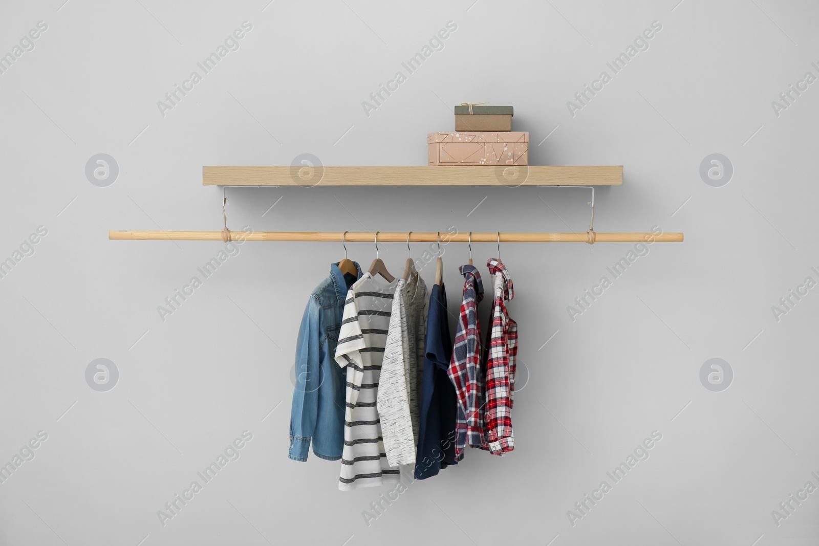 Photo of Rack with different clothes on light background