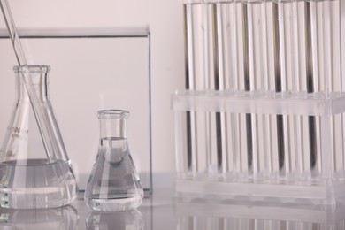 Laboratory analysis. Glass flasks and stirring rod on white table, space for text