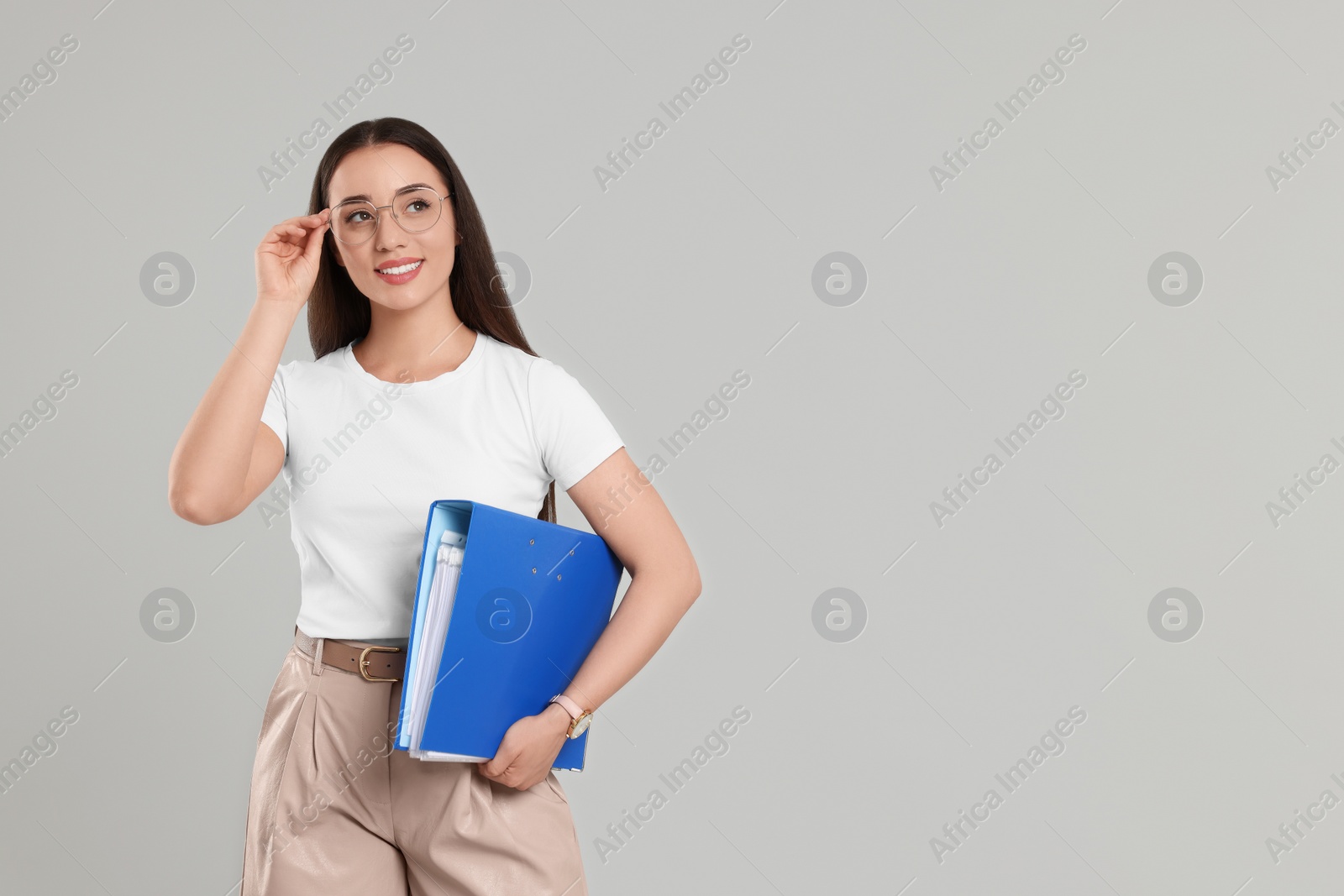 Photo of Happy woman with folder on light gray background, space for text