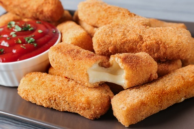 Photo of Plate of tasty crispy cheese sticks with sauce, closeup