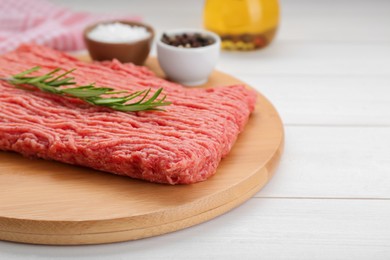 Raw fresh minced meat with rosemary on white wooden table, closeup. Space for text