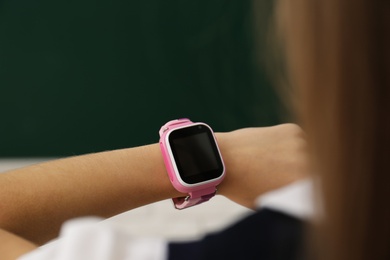 Photo of Girl with stylish smart watch in classroom, closeup