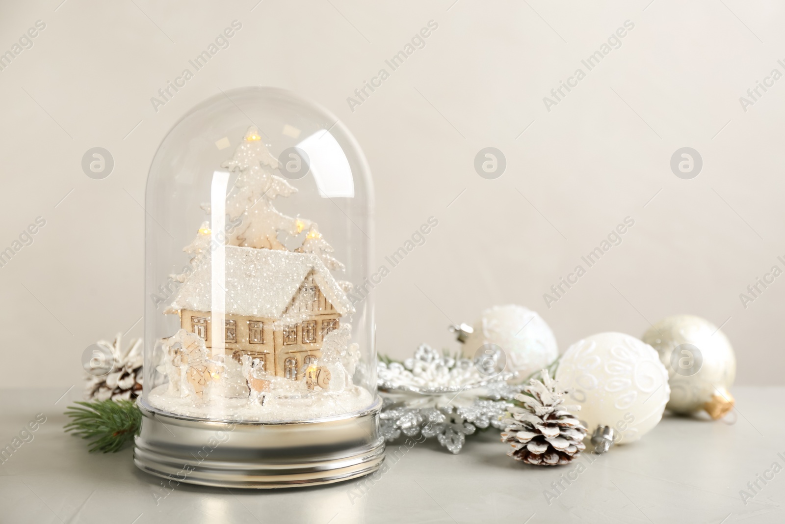 Photo of Beautiful snow globe and Christmas decor on light grey stone table. Space for text