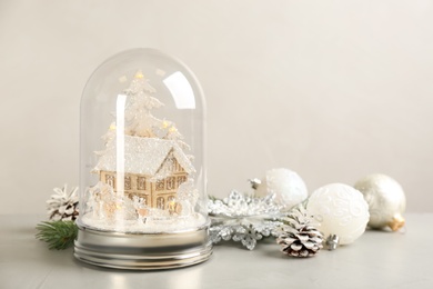 Photo of Beautiful snow globe and Christmas decor on light grey stone table. Space for text