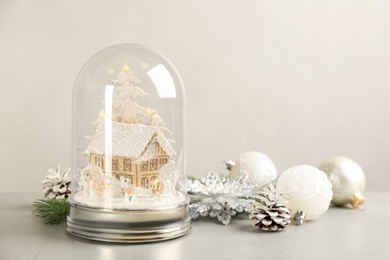 Beautiful snow globe and Christmas decor on light grey stone table. Space for text