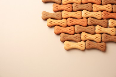 Photo of Bone shaped dog cookies on beige background, flat lay. Space for text