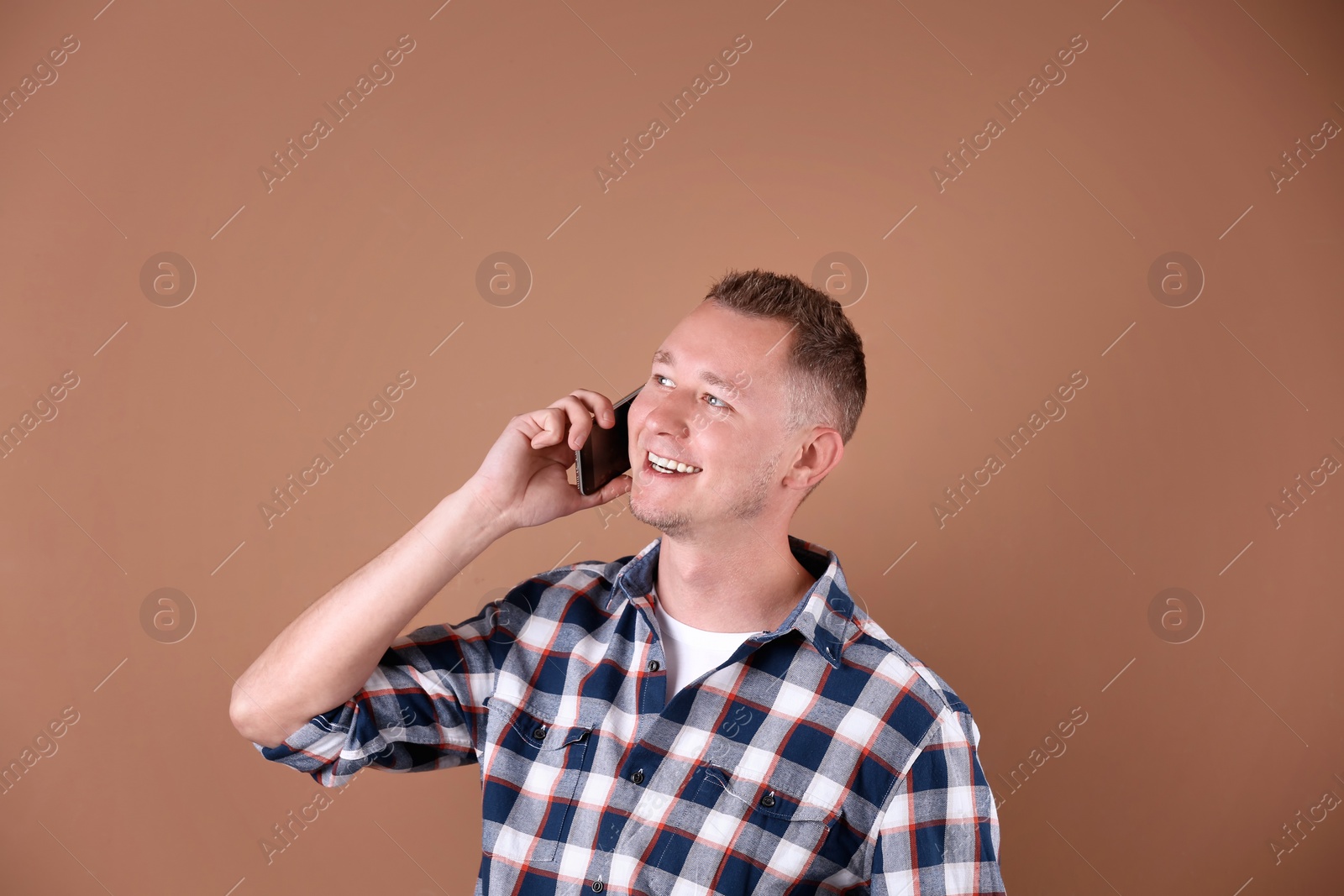 Photo of Portrait of handsome man with mobile phone on color background