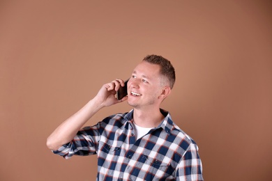 Photo of Portrait of handsome man with mobile phone on color background