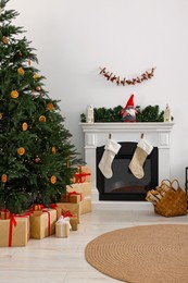 Many different gift boxes under Christmas tree and festive decor in living room