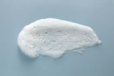 Photo of Smudge of white washing foam on color background, top view