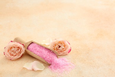 Photo of Pink sea salt and beautiful flowers on color textured table. Space for text