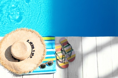 Photo of Flat lay composition with beach accessories on wooden deck near swimming pool. Space for text