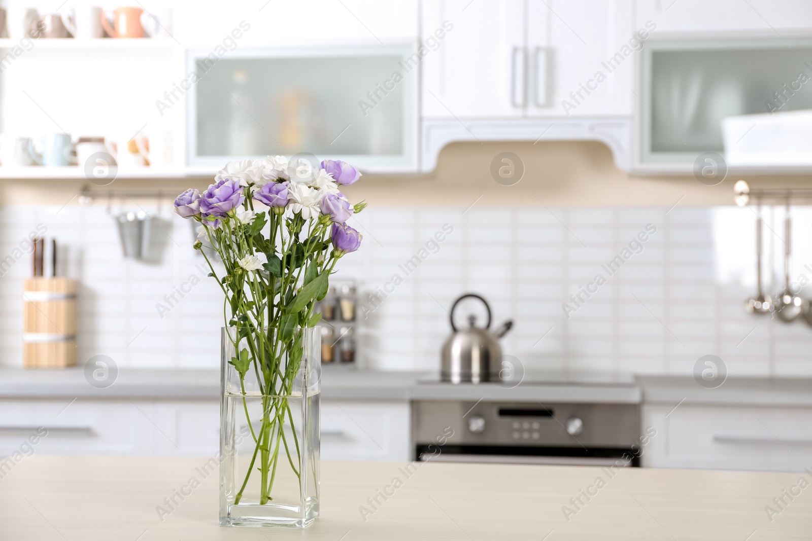 Photo of Vase with beautiful flowers on table in kitchen interior. Space for text