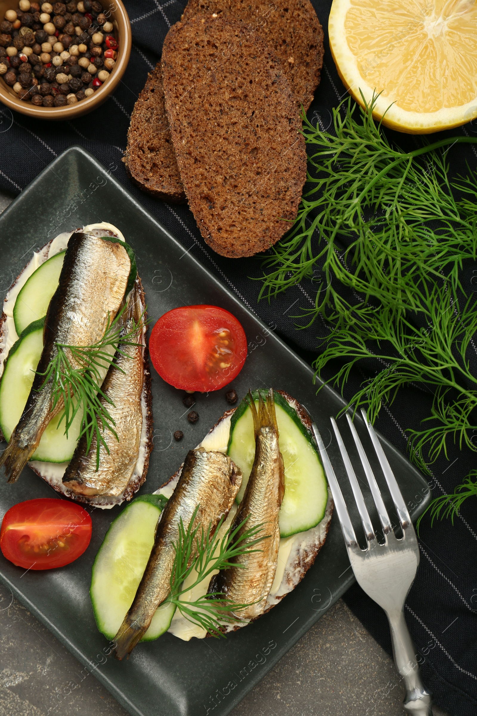 Delicious sandwiches with sprats, cucumber and dill served on grey table, flat lay Photo of Delicious sandwiches with sprats, cucumber and dill served on grey table, flat lay