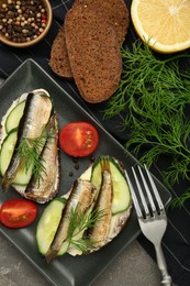 Photo of Delicious sandwiches with sprats, cucumber and dill served on grey table, flat lay