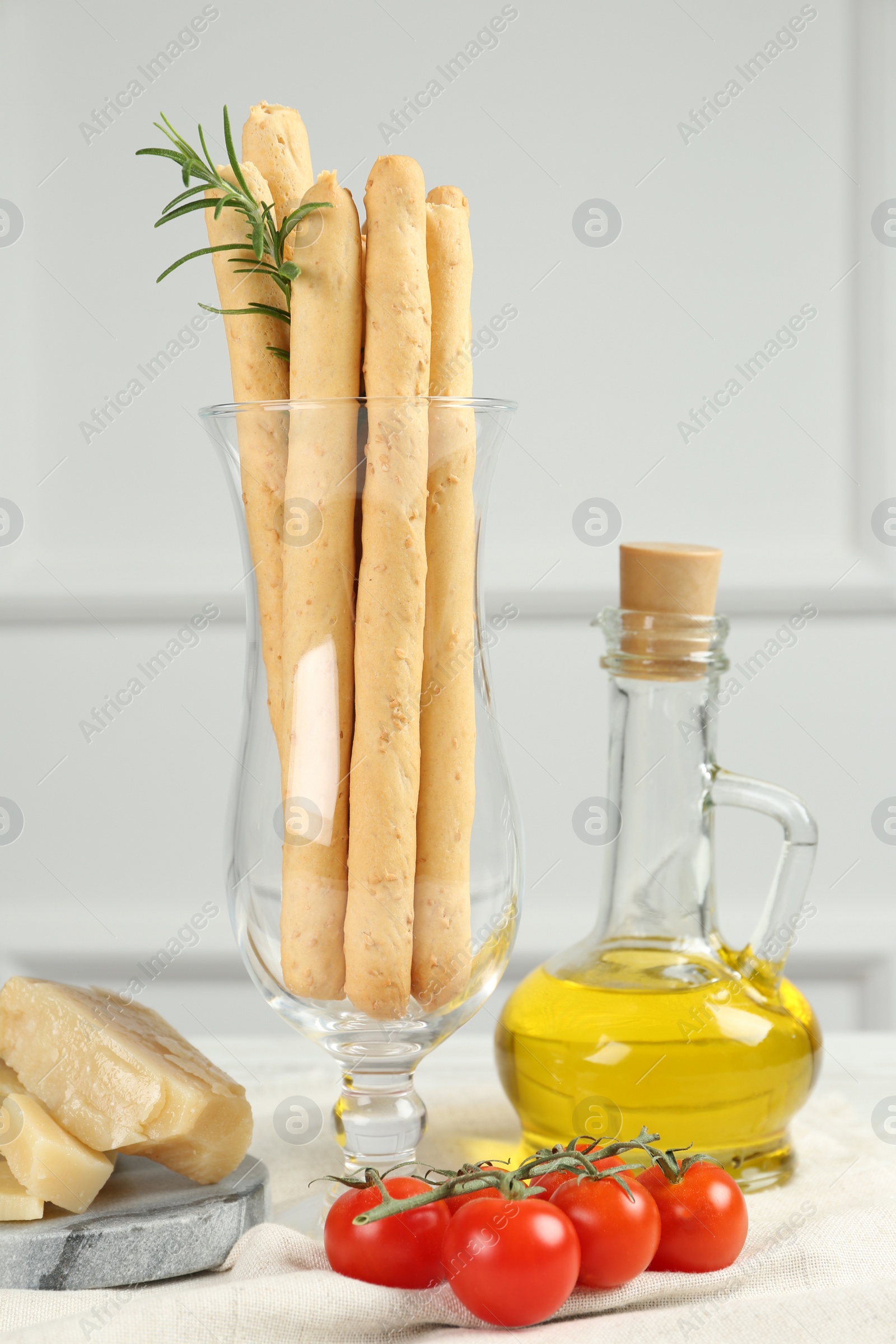 Photo of Tasty grissini with oil, tomatoes and cheese on table