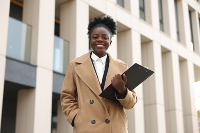 Photo of Happy woman with clipboard outdoors. Lawyer, businesswoman, accountant or manager