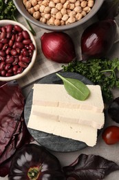 Photo of Tofu cheese and different vegetables on grey table, flat lay. Vegan diet