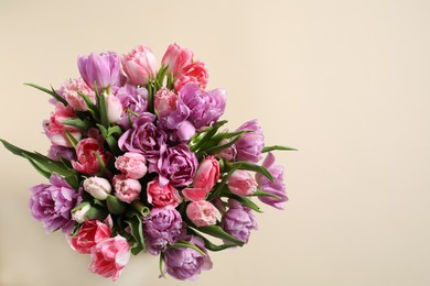 Photo of Beautiful bouquet of colorful tulip flowers on beige background, top view. Space for text