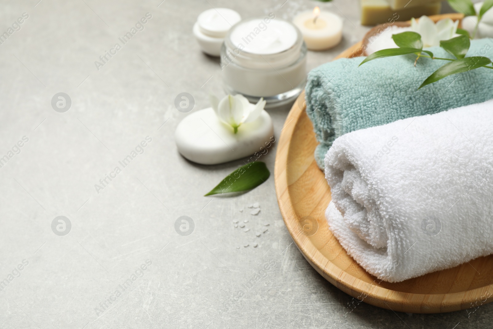 Photo of Spa composition with towels and skin care products on grey textured table, space for text