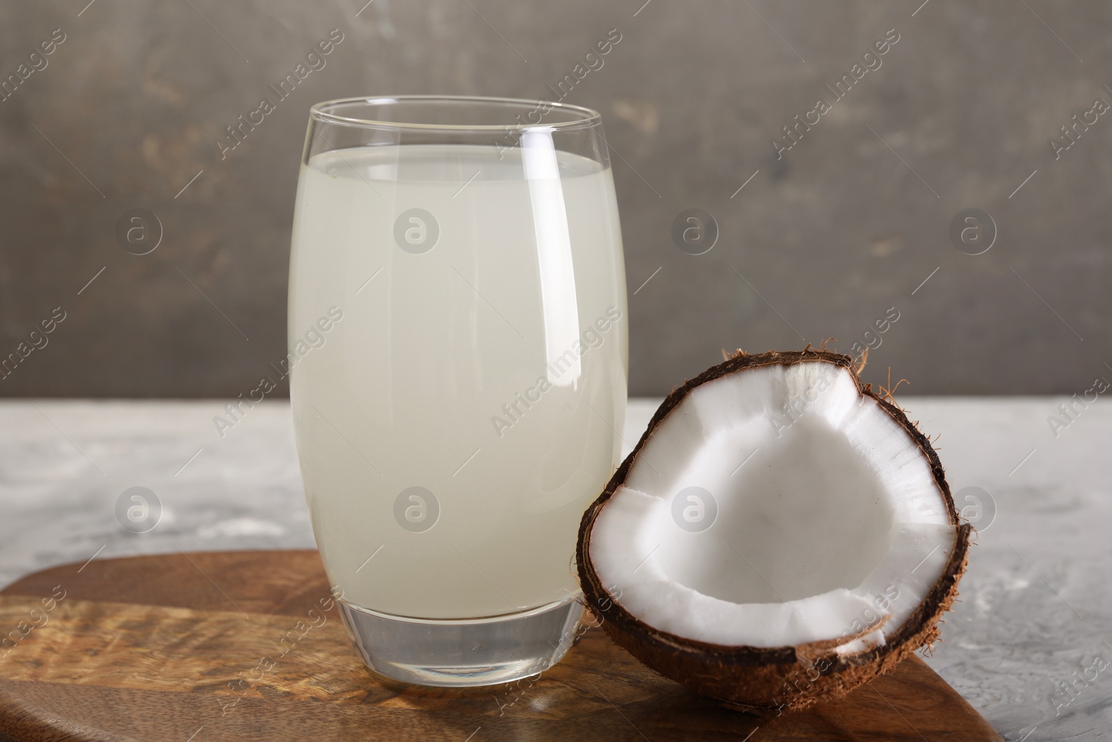 Photo of Glass of coconut water and nut on grey table