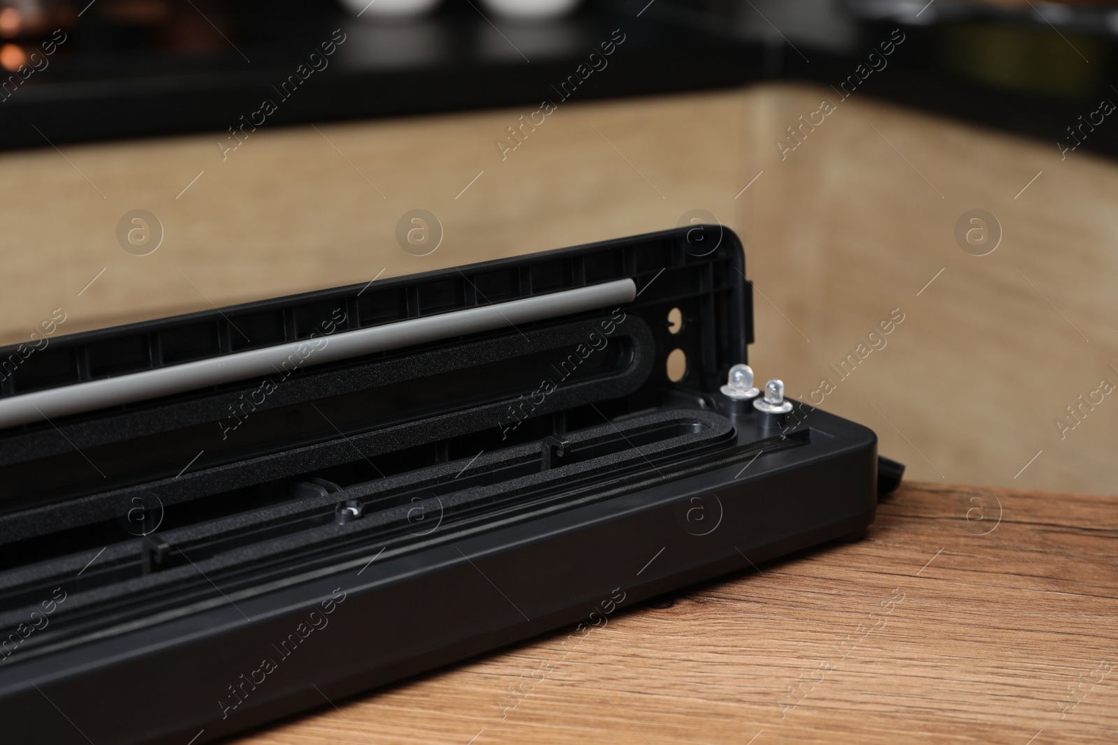 Photo of Sealer for vacuum packing on wooden table in kitchen, closeup