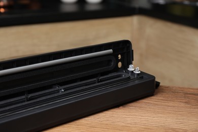 Photo of Sealer for vacuum packing on wooden table in kitchen, closeup