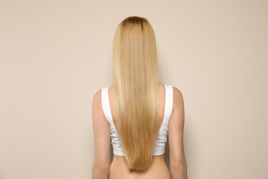 Photo of Young woman with long straight hair on beige background, back view