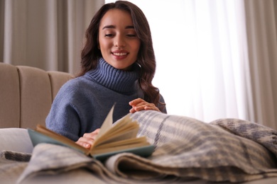 Photo of Young woman reading book at home. Winter atmosphere