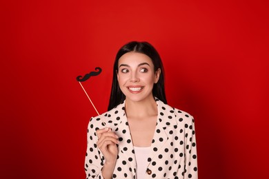 Emotional woman with fake mustache on red background