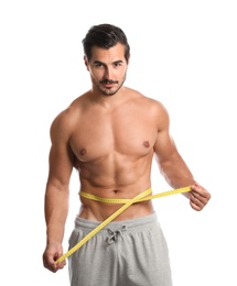 Young man with slim body using measuring tape on white background