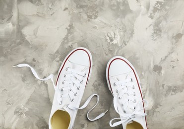 Photo of Pair of white sneakers on grey stone table, flat lay