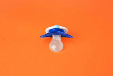 Photo of One blue baby pacifier on orange background