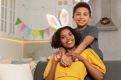 Photo of Happy African American mother with Easter eggs and her cute son in kitchen