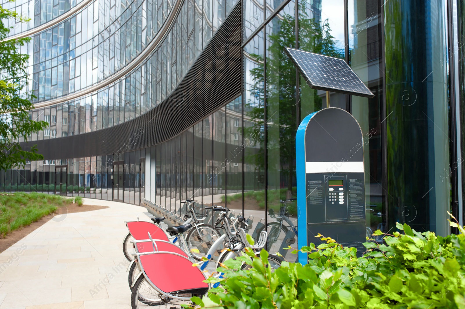 Photo of Payment terminal near parking lot with many bicycles outdoors