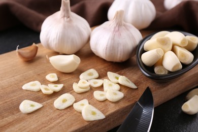 Aromatic cut garlic, cloves and bulbs on dark table, closeup