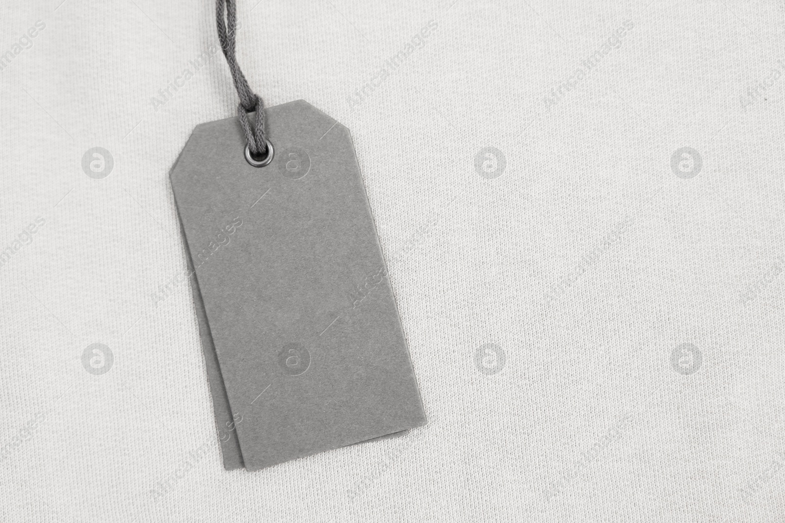 Photo of Cardboard tags on beige garment, top view. Space for text