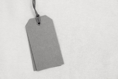 Cardboard tags on beige garment, top view. Space for text