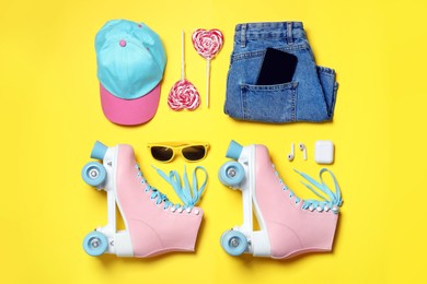 Photo of Flat lay composition with roller skates and clothes on yellow background