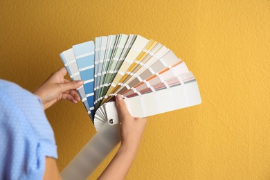 Photo of Female interior designer with palette samples on color background, closeup