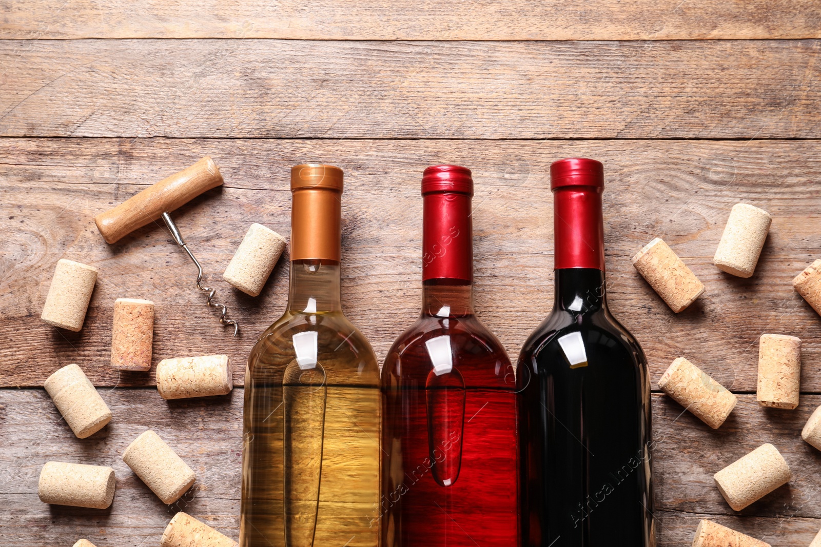 Photo of Flat lay composition with bottles of wine and corks on wooden table