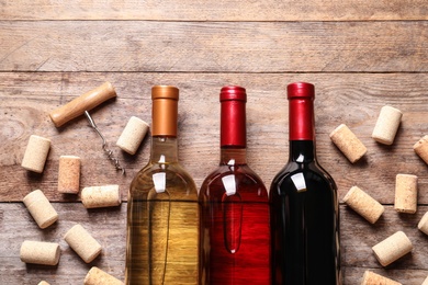 Flat lay composition with bottles of wine and corks on wooden table