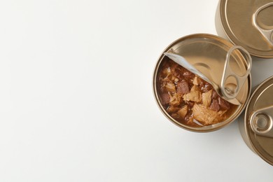 Photo of Tin cans with wet cat food on white background, top view. Space for text