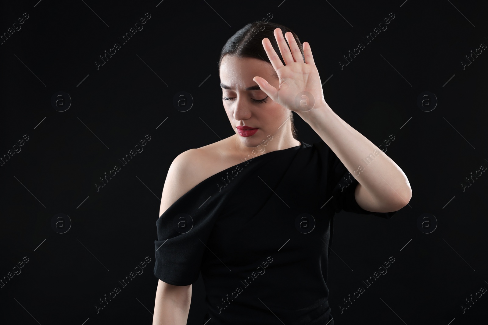 Photo of Beautiful woman covering face with hand on black background