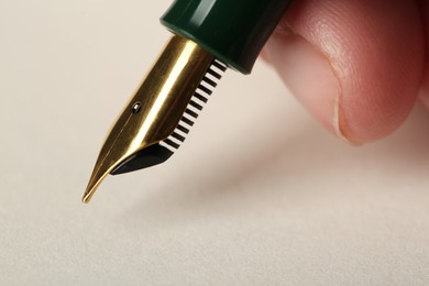 Woman with fountain pen above light paper, closeup